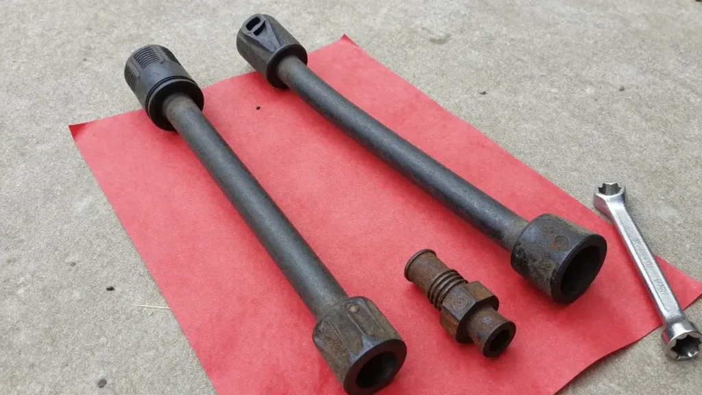 New tie rod end and sway bar link beside the worn parts on a driveway